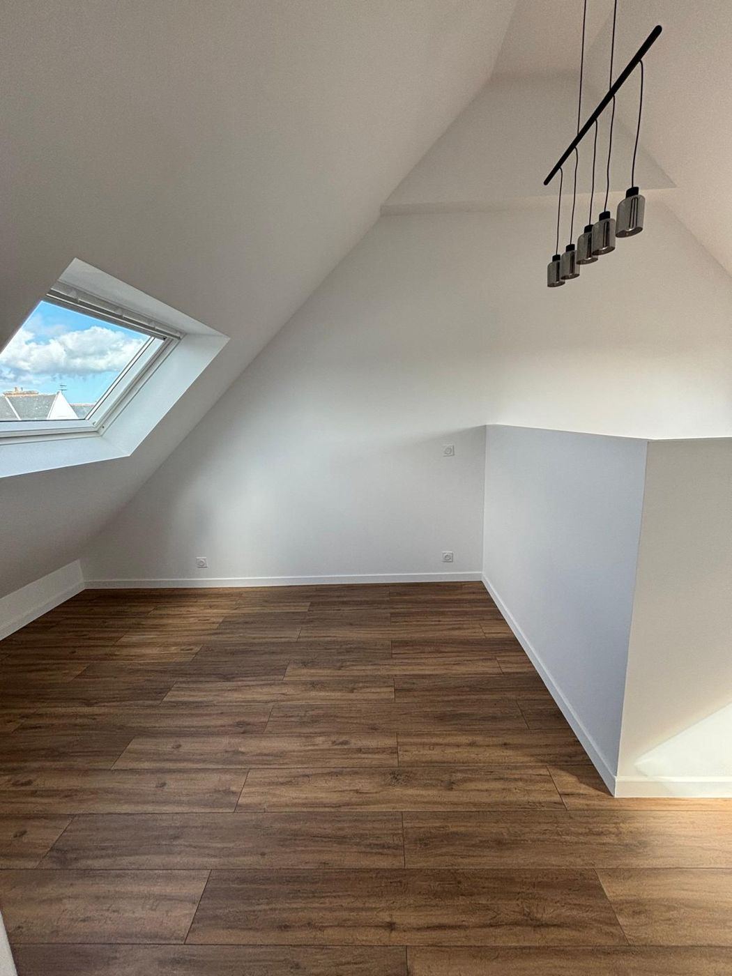 Chambre sous combles avec fenêtre de toit et suspension