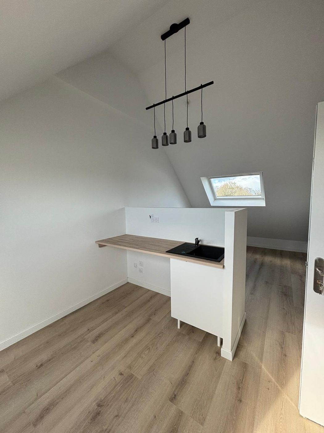 Kitchenette avec plan de travail bois et évier noir